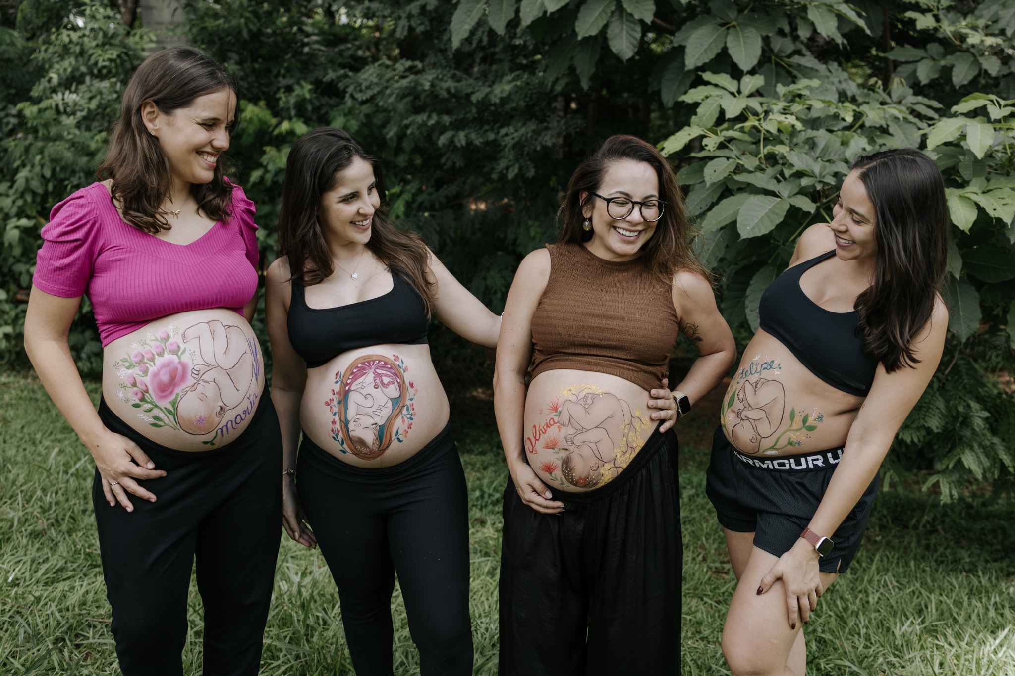 Grupo de mulheres mostrando diferentes pinturas gestacionais