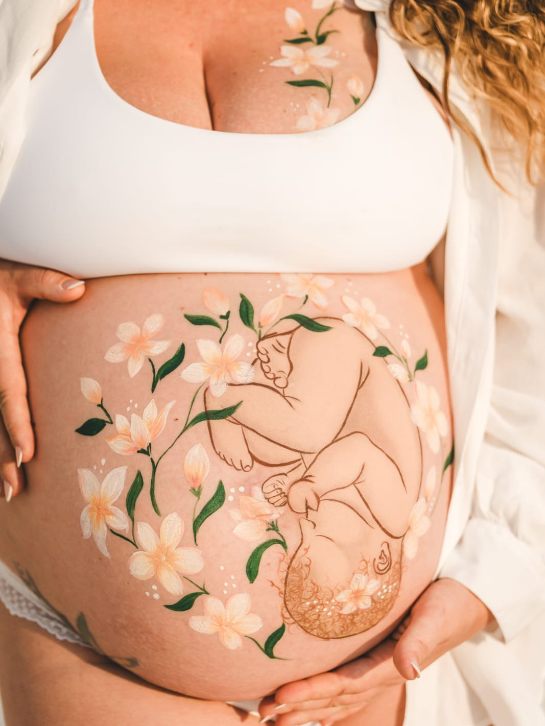 Pintura gestacional com bebê e flores brancas