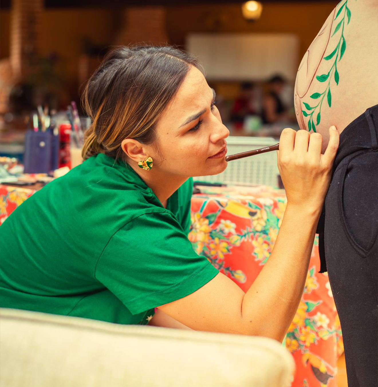 Artista pintando uma composição botânica em uma barriga gestante